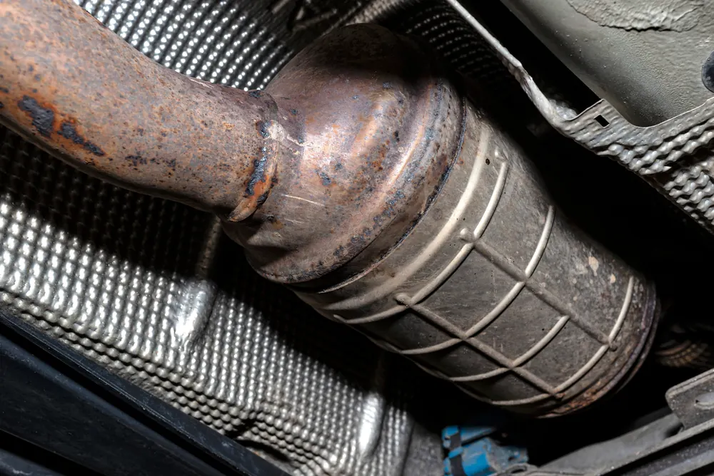 Corroded diesel particulate filter still fitted under a vehicle before removal for cleaning